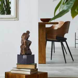Rodin The Thinker bronze statue displayed on library shelf beside books as desk and library art