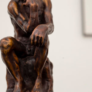 Close-up of Rodin The Thinker classical bronze statue showing detailed muscular figure and seated pose