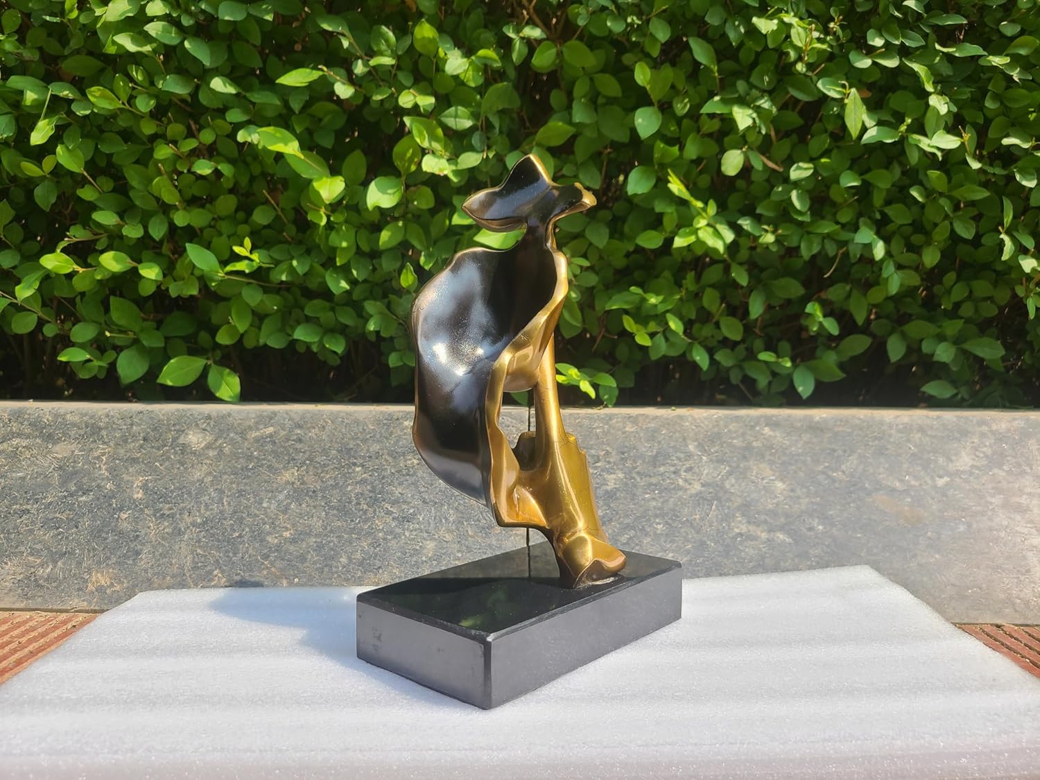 Side view of gold finish Silence is Gold thinker bronze sculpture on black marble base