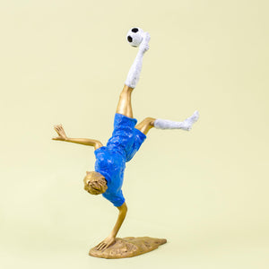 Full dynamic view of gold soccer player bicycle kick sculpture showing athletic movement