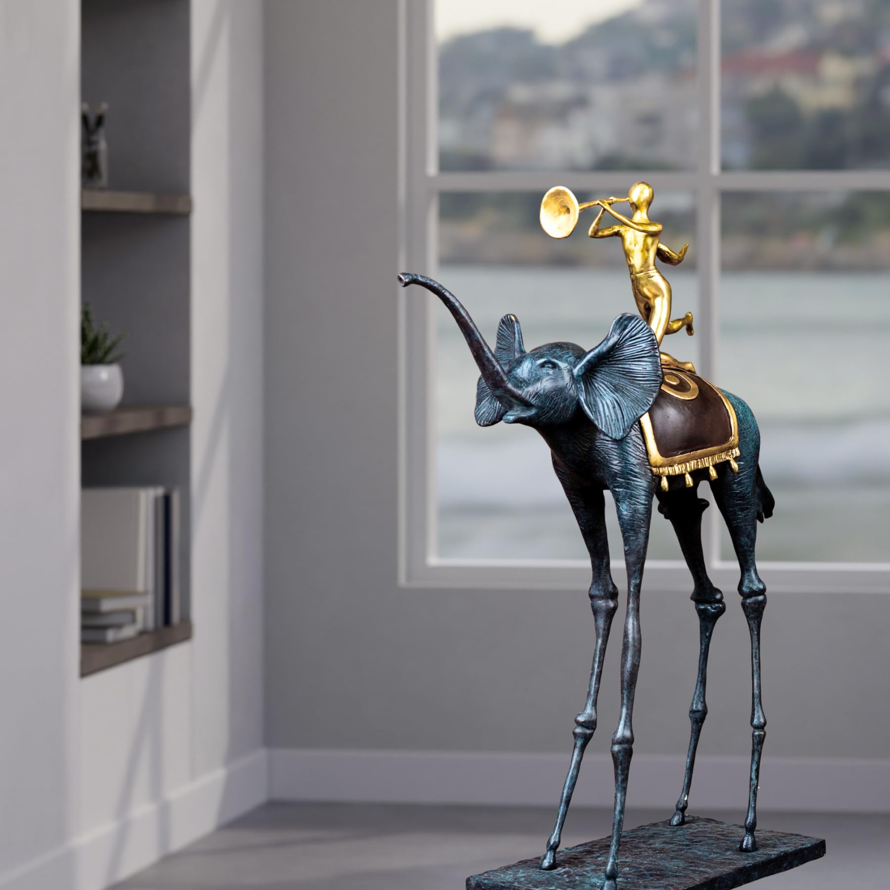 Surrealist bronze elephant statue displayed beside bookshelf in modern interior room