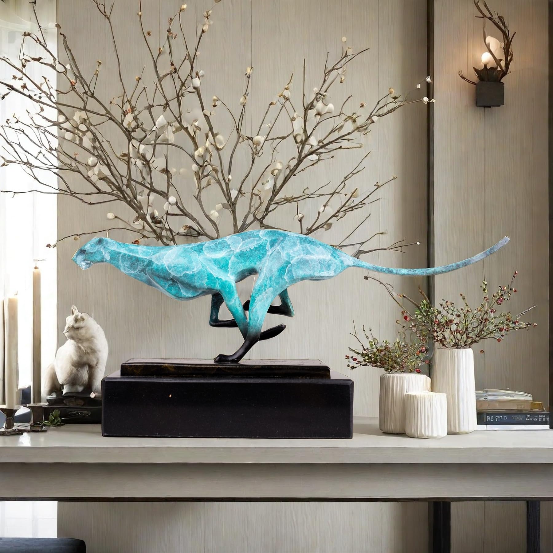 Teal azure running cheetah sculpture on marble base styled with dried branch in luxury interior