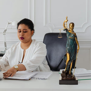 Teal bronze Lady Justice Themis statue in modern office with floor-to-ceiling window interior display