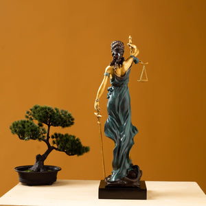 Teal bronze Lady Justice Themis statue in modern office with floor-to-ceiling window interior display