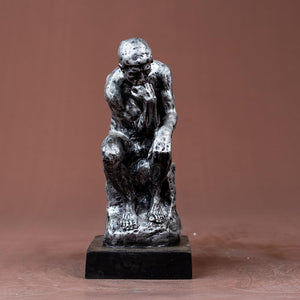 The Thinker gothic obsidian silver statue front view on warm brown background with black pedestal base