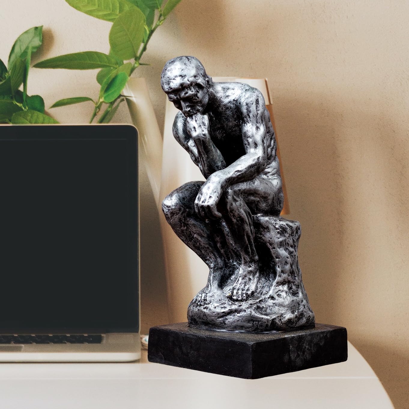 The Thinker gothic obsidian silver bronze statue displayed on desk beside laptop in home office setting