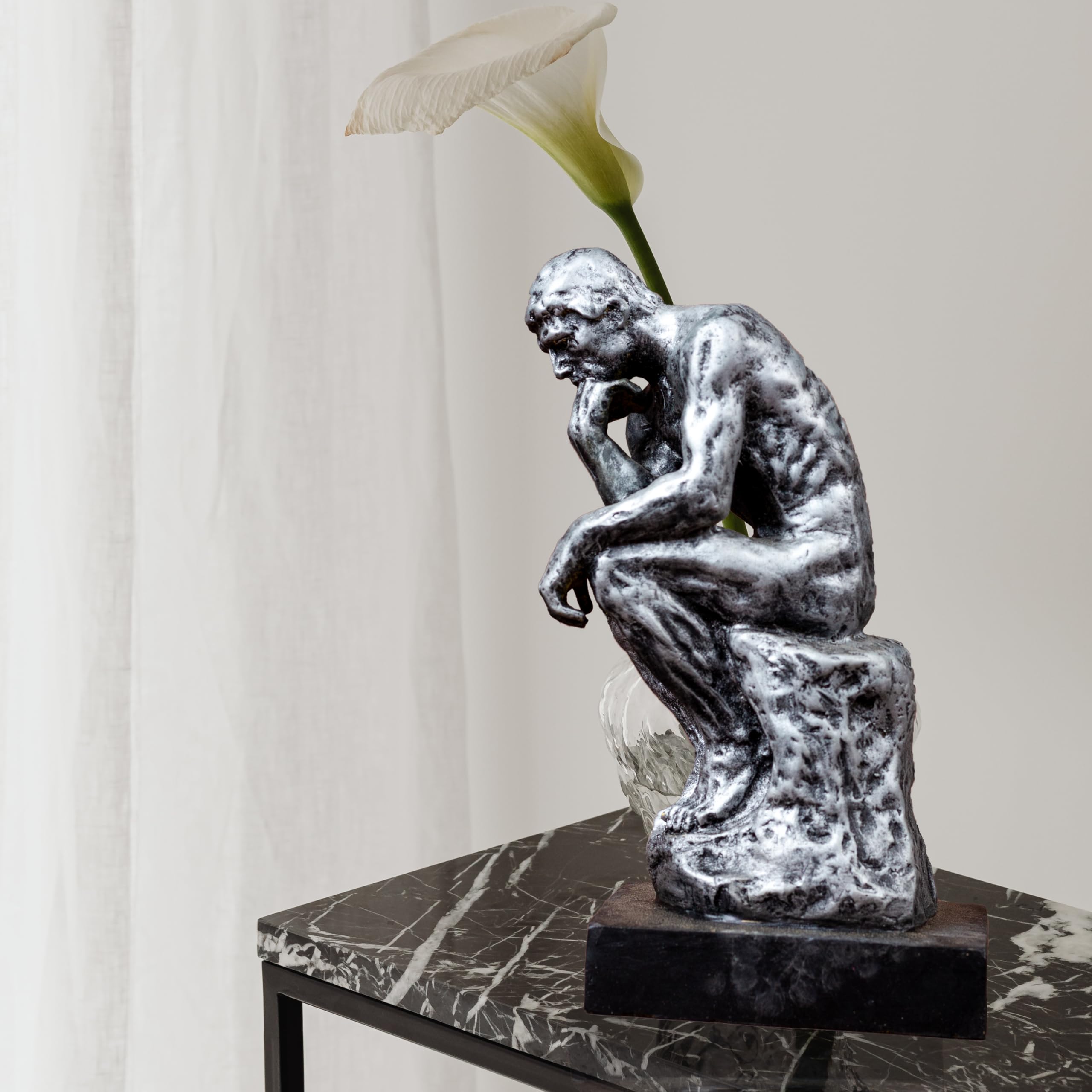 The Thinker gothic silver bronze statue displayed on side table beside lily flower decor