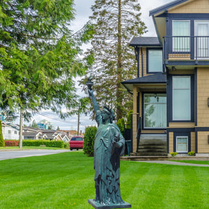 Verdigris blue bronze Statue of Liberty displayed on lawn garden in front of luxury house exterior