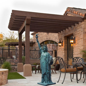 Verdigris blue bronze Statue of Liberty displayed in outdoor pergola patio with furniture setting