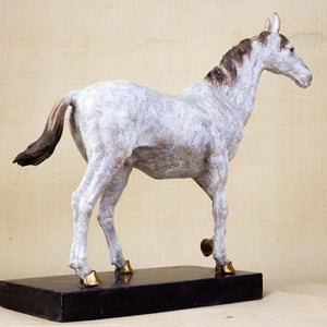 White bronze walking horse sculpture with golden hooves side full body view on warm brown background