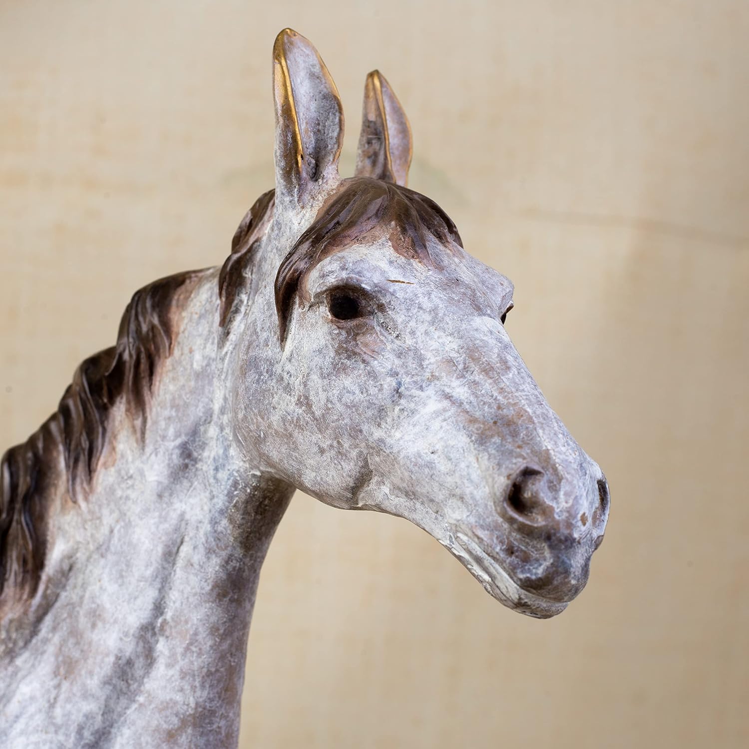 Close-up front detail of white bronze horse sculpture head showing dappled patina and mane texture