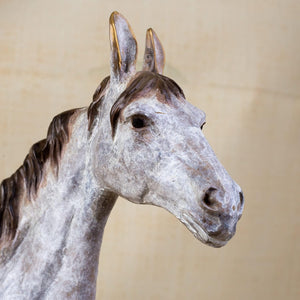Close-up front detail of white bronze horse sculpture head showing dappled patina and mane texture